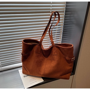 Close-up of brown suede tote bag with adjustable side straps and gold hardware detail