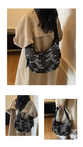Detail of black quilted nylon crossbody bag with white embroidery and wide strap