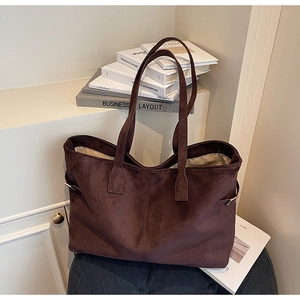 Detailed view of large dark brown suede tote bag with metal buckles on side