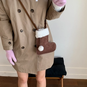 Détail d'un sac bandoulière botte de Noël en daim marron avec bordure en polaire blanche