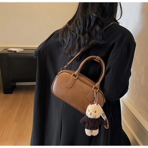 Close-up of brown textured leather crossbody bag featuring a cute plush bear charm