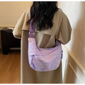 Detail of purple quilted crescent crossbody bag with embroidery and adjustable wide strap