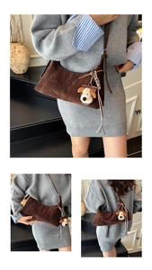 Detail of dark brown wax leather crescent hobo bag with plush dog charm and tassels