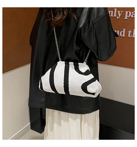 Detail of black and white knitted cloud bag with silver chain strap worn by model