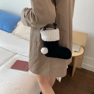 Détail d'un sac bandoulière en forme de chaussette de Noël en daim noir et fausse fourrure blanche