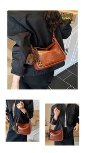 Détail d'un sac à bandoulière en cuir marron brillant avec pompon et sangle perlée