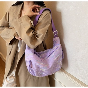 Detailed shot of purple quilted crossbody bag featuring vibrant colorful wavy embroidery