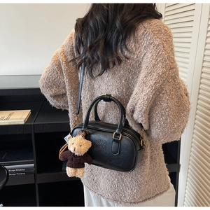 Detail of black leather cylinder bag with Mira Mira embossing and teddy bear charm