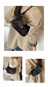 Détail d'un sac hobo noir en cuir ciré avec un pendentif en peluche marron clair