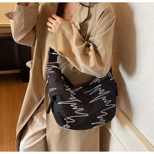 Detailed close-up of black quilted crossbody bag with white zigzag stitching and nylon strap
