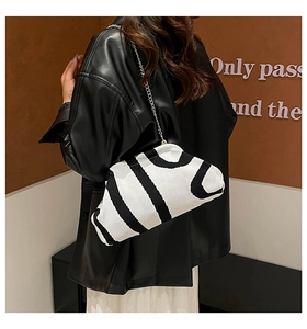 Detailed macro view of black and white knitted cloud bag with silver chain strap and wavy patterns