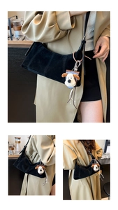 Detail view of black matte crescent bag with stitch design and plush puppy charm accessory