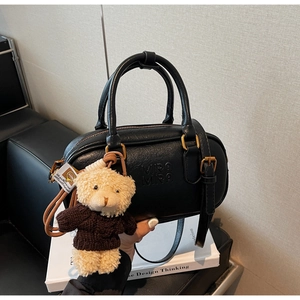 Close-up of black Boston bag with MIRA MIRA embossed logo and cute teddy bear charm