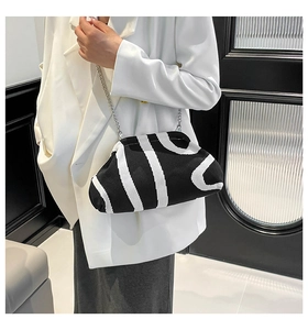 Detail of black and white striped knitted cloud bag with silver chain strap on white blazer