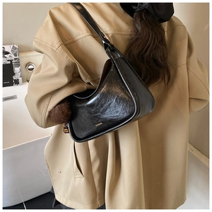 Vue détaillée du sac bandoulière vintage en cuir huilé noir avec logo doré