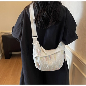 Detailed view of white textured crescent crossbody bag with colorful artistic embroidery