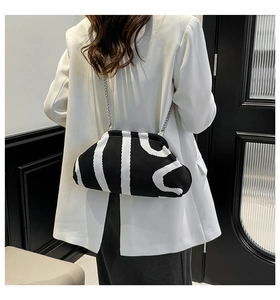 Minimalist black and white knitted cloud bag with silver chain worn on white blazer