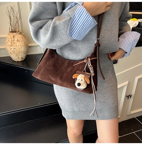 Detail of dark brown vintage crescent bag with woven knot and cute plush dog pendant