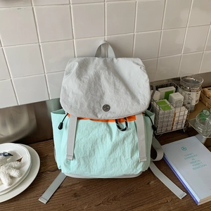 Detail of color-block canvas backpack featuring drawstring closure and top handle strap