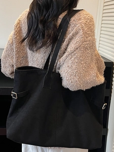 Large black suede tote bag with metal buckle detail shown on shoulder for daily commute