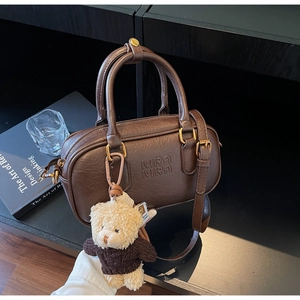 Detail of dark brown Boston bag featuring vintage PU texture and a cute bear charm pendant