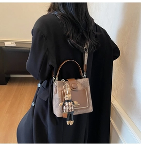 Close-up of brown bucket bag with wide patterned strap and a cute rabbit charm
