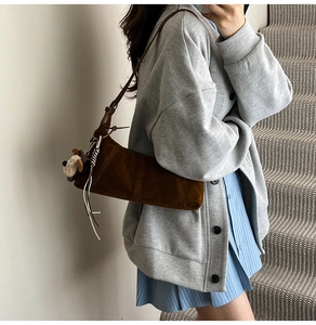Detail of brown suede hobo bag with silver tassels and cute puppy charm accessory