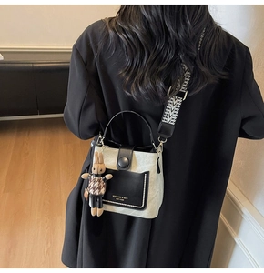 Detail of two-tone bucket bag with silver beaded trim and geometric woven strap