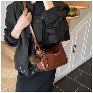 Détail du sac bandoulière marron foncé vintage avec pompon et large bandoulière