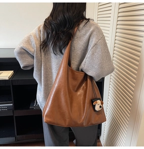 Detail of a large vintage brown tote bag with a cute plush dog charm on a shoulder strap