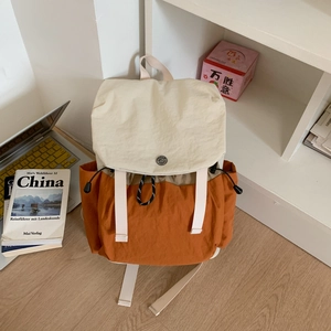 Detail view of contrast color canvas backpack with side drawstring pockets and metal buckle