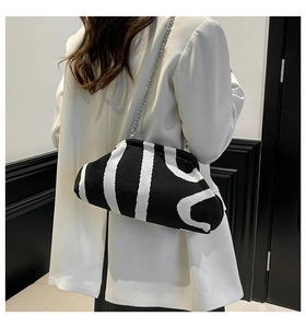Close-up of black and white striped knitted clutch bag with silver chain strap detail