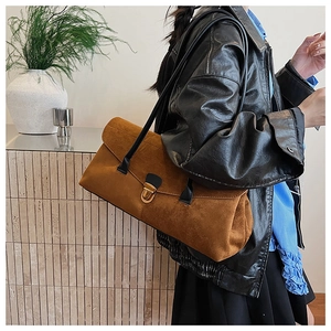 Detail of vintage brown suede shoulder bag with gold clasp shown on a model