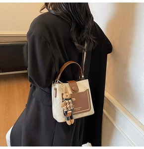 Detail view of a retro cream and brown bucket bag with a cute rabbit doll charm