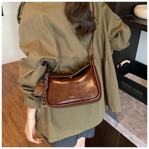 Gros plan du sac à main marron vintage avec breloque en peluche et bandoulière texturée