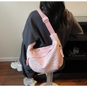 Detailed close-up of pink quilted crossbody bag with textured fabric and adjustable strap