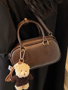 Brown vintage Boston bag with shoulder strap and plush bear charm for autumn style