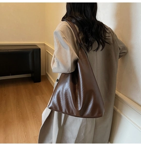 Detailed close-up showing the smooth leather texture and stitching of the brown tote bag