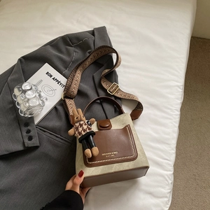 Detail of retro bucket bag with patterned strap, leather trim and bunny charm
