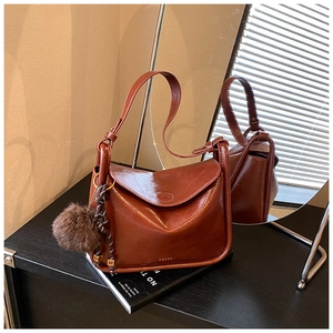 Sac bandoulière rétro marron avec pompon en fourrure et détails dorés sur un bureau
