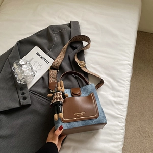 Detail of denim and leather bucket bag with gold rivets and ethnic woven shoulder strap