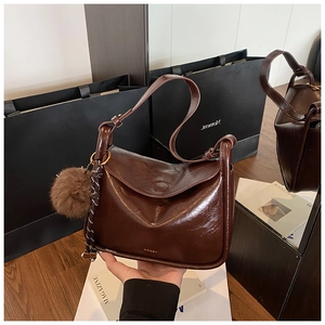 Détail du sac de selle marron vintage avec pompon en peluche et bandoulière décorative