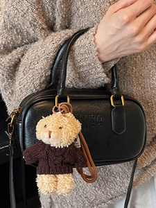 Chic black faux leather Boston bag with gold hardware and a cute teddy bear pendant