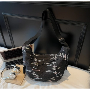 Quilted black crossbody bag with vibrant embroidery and adjustable wide strap