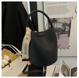 Detail of black lychee grain leather bucket bag with chic fashion print ribbon and gold hardware
