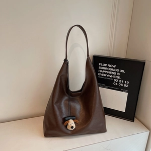 Detail of deep brown faux leather tote bag with a cute beige puppy plush pendant