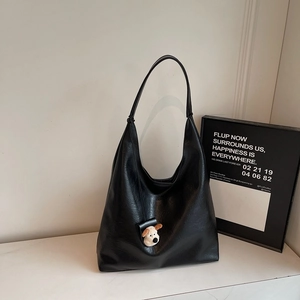 Detail of black large Hobo shoulder bag with leather texture and cute dog charm