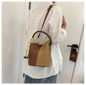 Detail view of two-tone leather bucket bag with fashion webbing and adjustable strap