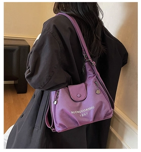Detail view of purple nylon hobo bag featuring front flap pocket and logo pendant