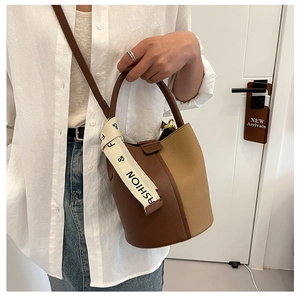 Detail of contrast stitching bucket bag featuring pebble leather and wide fashion strap